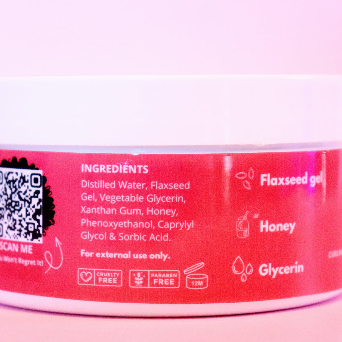 Close-up of Reclaim Your Crown Flaxseed Gel unscented product label with ingredients listed on a pink background
